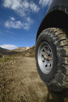 Big car wheel on mountains at day backdrop. Offroad 4x4 concept