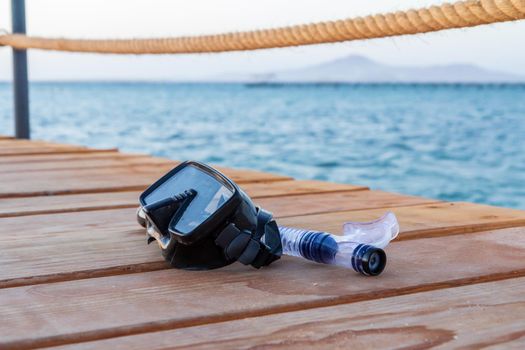 Dive mask and snorkel for professionals on wooden pier.