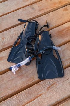 Swimming fins, dive mask and snorkel for professionals on wooden pier.