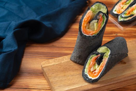 Black tortilla wrap with salted salmon and vegetables