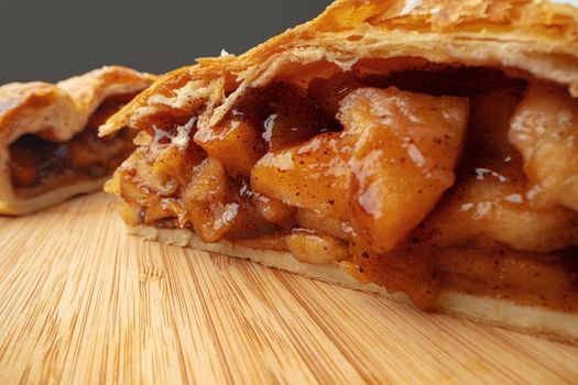 Apple pie on a wooden board cut into pieces
