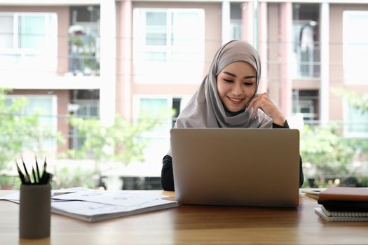 Muslim woman working with laptop computer in office , writing paper. Confidence pretty muslim woman Business and finance concept.