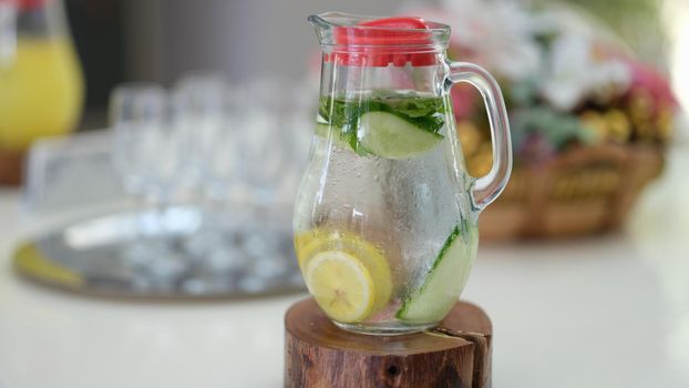 Glass jug of detox water with lemon and cucumber standing on table closeup