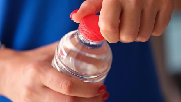 Female hands opening plastic water bottle closeup