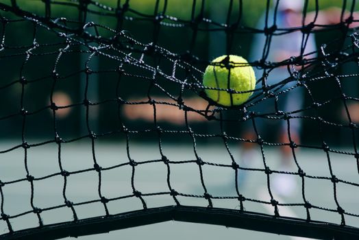 Thats a lost point. Cropped shot of a tennis ball hitting a tennis net on the court during the day.