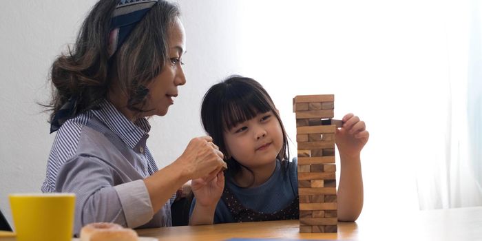 Little girl with her grandma playing jenga game at home