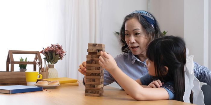 Little girl with her grandma playing jenga game at home