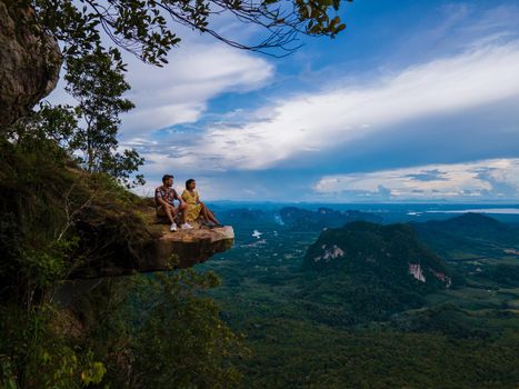 Dragon Crest mountain Krabi Thailand, a Young traveler sits on a rock that overhangs the abyss, with a beautiful landscape. Dragon Crest or Khuan Sai at Khao Ngon Nak Nature Trail