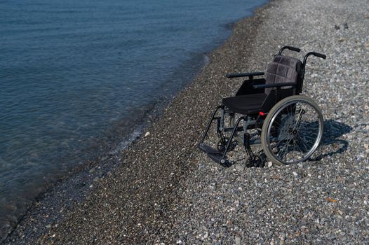An empty wheelchair on a rocky seashore.