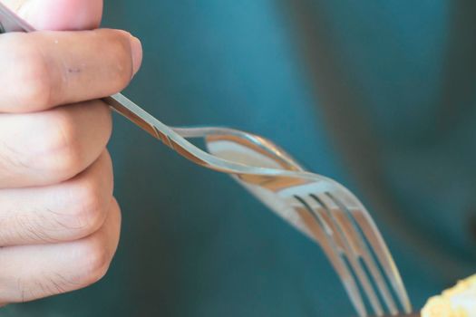 Male hands hold a fork over blur green background for food cooking