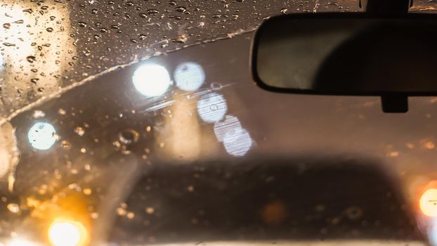 Interior of car when rains. Defocused blur of light on the road in a raining day