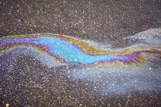 Oil stain on the asphalt, rainbow-shaped colored gasoline stains on an asphalt road