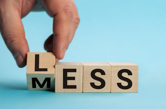 Less mess words on wooden blocks. Turned the cube and changed the word mess to less. Blue background, copy space. Business and less mess concept.