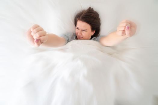 Portrait of young beautiful woman in bed stretching in the morning with motion blur effect