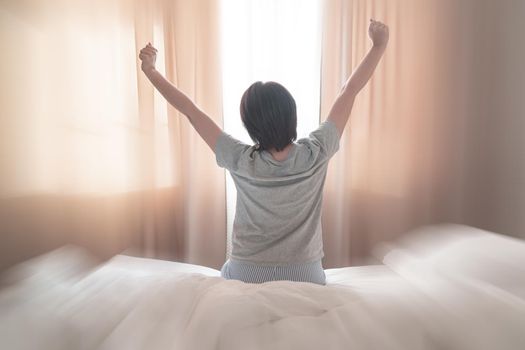 Woman stretching in bed after wake up, soft tone with motion blur effect