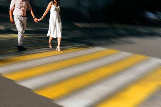 Caucasian couple holding hands crossing city intersection with motion blur effect