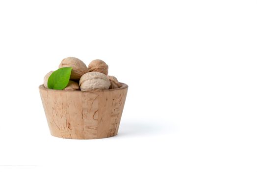 Walnut. Walnut fruits of different varieties lie in wooden saucers and baskets on a white isolated background. Nearby are green leaves and unripe walnut fruits.