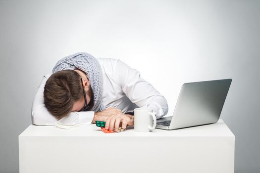 man sitting in office is snoozing at his work place near laptop.