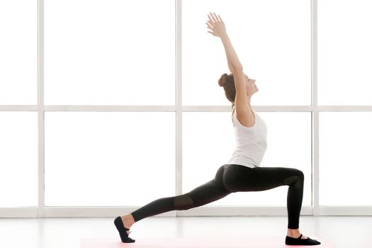 Woman looking up, hands up and doing yoga, warrior one posture