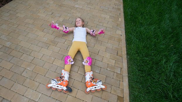 Little girl learns to roller skate and falls. View from above