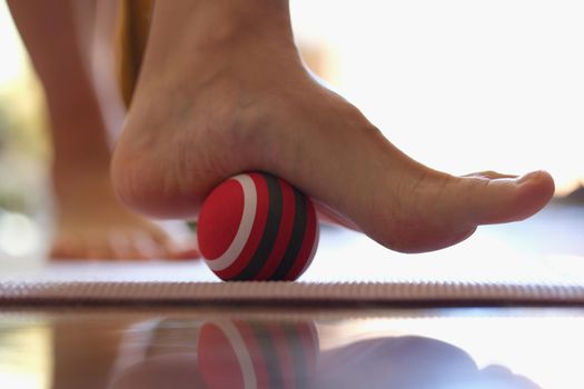 Person rolls massage ball with foot of foot closeup
