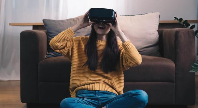 Asian woman play VR game for entertain at home, asian woman joyful in house on holiday. Happy woman playing metaverse VR technology concept.