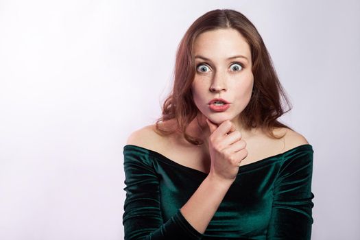 Portrait of shocked unbelieved woman with freckles and classic green dress.