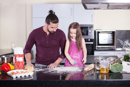 happy father with his little daughter preparing food in their kitchen