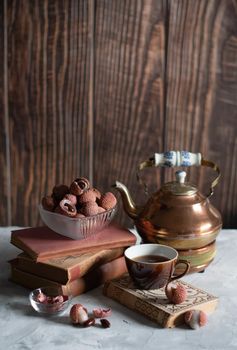 still life with lychee fruit and a vintage copper teapot with books on a wooden