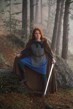 Portrait red-haired girl in armor and raincoat in forest