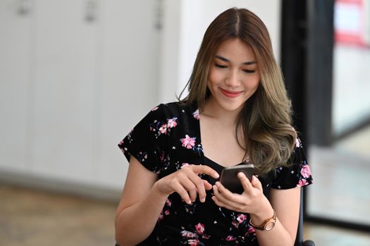 Serene young woman shopping online, checking social media on her smart phone.
