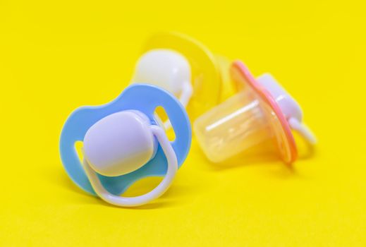 Dummy pacifiers for newborns in different colors. Selective focus.