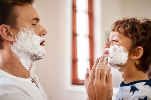 First we have to lather up. Shot of a man teaching his young son how to shave at home.