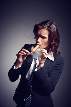 Time to light up. A businesswoman wearing a suit and tie while lighting a cigar.