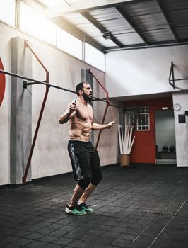 This is a great way to start my workout regime. Shot of a young man skipping rope in a gym.