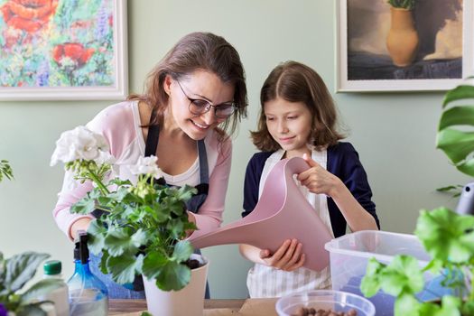 Mother and daughter kid together take care of indoor plants in pots