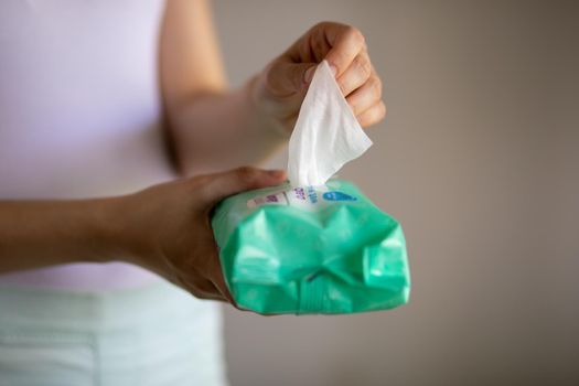 Woman taking wet baby wipes from the packaging - care for clean skin and surfaces
