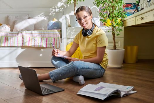 Teenage girl with glasses studying at home using a laptop