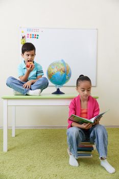 Preschool children playing with books sitting at a table