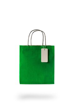 Green color paper shopping bag on white isolated background. An empty price tag hangs to insert text.