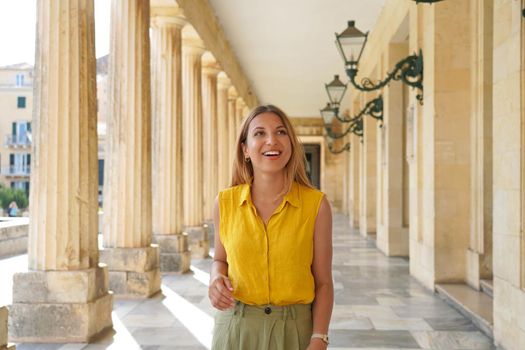 Portrait of young cheerful woman doing cultural tourism in Europe