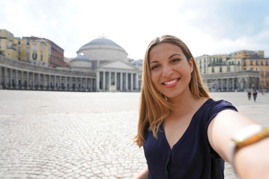 Happy smiling girl taking selfie photo in Naples with Piazza del Plebiscito square on the background, Naples, Italy