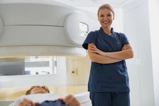 Portrait of doctor radiologist on background of MRI or CT Scan with patient undergoing procedure