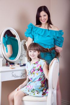 Mother hairdressing her preteen beautiful daughter