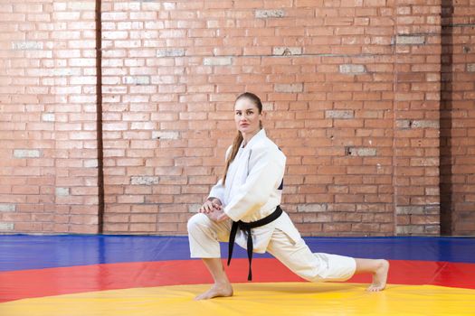 athletic karate woman in white kimono with black belt