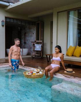 couple men and woman having breakfast in pool at a pool villa during vacation