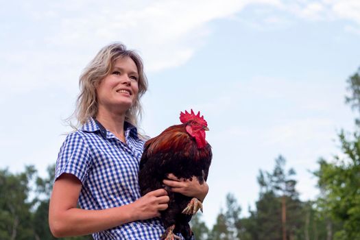 Beautiful woman in the farm holding a chicken, healthy lifestyle