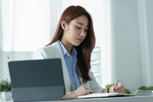 Portrait of a young businesswoman or business owner working with a notebook and tablet computer at office room