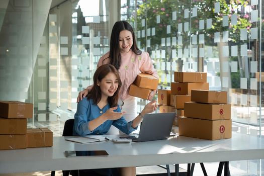 startup small business owner working at workplace. two asian wooman freelance seller check product order for delivery. Online selling, e-commerce, shipping concept