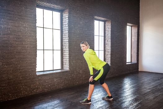 Sport, fitness concept. Woman in sportswear posing near brick wall.